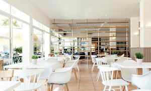 Lys og moderne restaurant med hvite møbler og grønne planter. (AI-generert tekst)