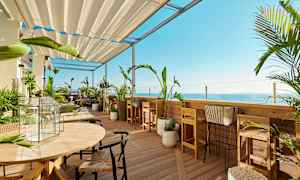 En terrasse med hagemøbler og planter med utsikt mot havet. (AI-generert tekst)