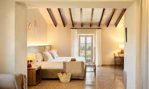 Soverom med lys innredning, dobbeltseng og utsikt gjennom glassdører. (AI-generert tekst)