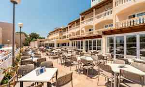 Terrasserestaurant med bord og stoler, omgitt av en bygning med balkonger. (AI-generert tekst)