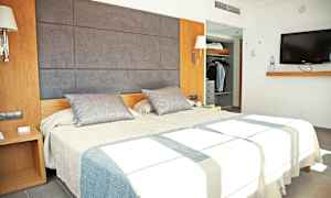 Bilde som viser et moderne hotellrom med en dobbeltseng, et garderobeskap og en veggmontert TV. (AI-generert tekst)