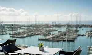 En utsikt over en marina med bord og stoler i forgrunnen. (AI-generert tekst)