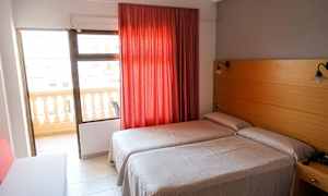 Hotellrom med to enkeltsenger, rød gardin og balkong. (AI-generert tekst)