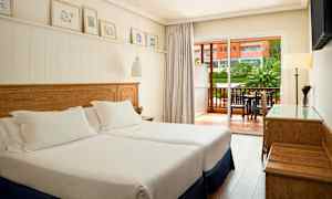 Et hotellrom med to enkeltsenger og en balkong utenfor. (AI-generert tekst)