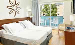 Bilde av et lyst hotellrom med to enkeltsenger, en dekorativ veggdekorasjon, en balkong med utemøbler og lyse gardiner. (AI-generert tekst)