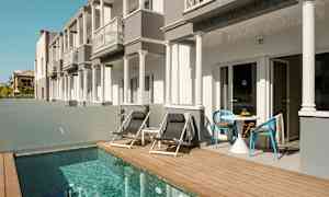 Bygninger med terrasse ved siden av et lite basseng. (AI-generert tekst)