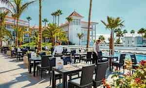 Restaurantområde med uteservering, omgitt av palmer og bassenger. (AI-generert tekst)