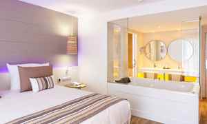 Hotellrom med en seng og et innebygd boblebad som vender mot et bad. (AI-generert tekst)