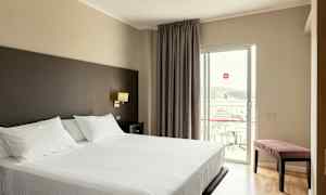 Hotellrom med en dobbeltseng og balkong. (AI-generert tekst)