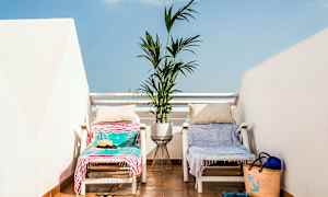 To solsenger med håndklær og puter står på en terrasse med en blomsterpotte mellom seg. (AI-generert tekst)