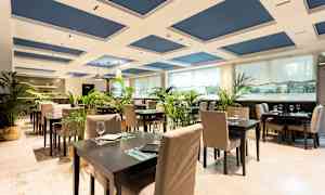 Et elegant restaurantområde med bord og stoler, dekorert med grønne planter. (AI-generert tekst)