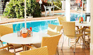 Utendørsområde med bord og stoler ved et basseng. (AI-generert tekst)