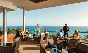 Personer som sitter på en terrasse med havutsikt. (AI-generert tekst)