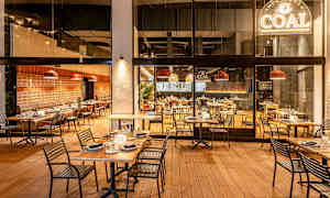 Restaurant med utendørs- og innendørs sitteplasser, dekorert med tretrekk og moderne møbler. (AI-generert tekst)