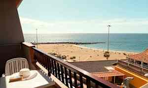 En balkong med utsikt over en sandstrand og havet. (AI-generert tekst)