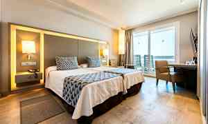 Et hotellrom med to enkeltsenger, moderne møbler og en balkong med utsikt. (AI-generert tekst)