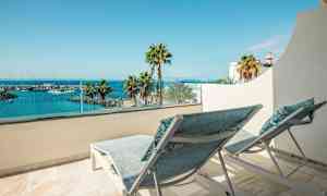 To solsenger på en balkong med utsikt over en havn og sjøen. (AI-generert tekst)