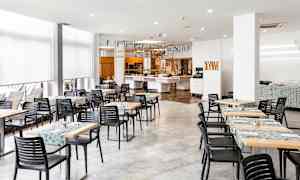 En spisesal med bord og stoler samt dekorasjoner i taket. (AI-generert tekst)