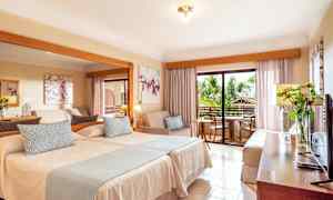 Hotellrom med to senger, en sittegruppe og en balkong. (AI-generert tekst)