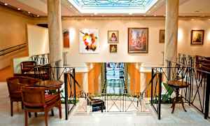 Interiør av en elegant bygning med kunstverk på veggene og sitteplasser rundt om. (AI-generert tekst)