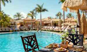 Frokost servert ved et bord ved et basseng med solsenger og parasoller i bakgrunnen. (AI-generert tekst)