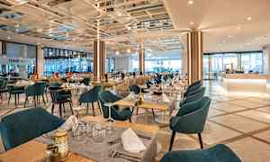 En restaurant med bord og stoler dekket til. (AI-generert tekst)