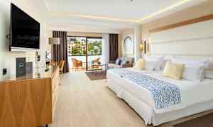 Et hotellrom med to senger, sittegruppe og balkong. (AI-generert tekst)