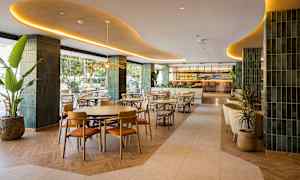 En elegant restaurant med moderne møbler og interiør, beliggende innendørs med grønne detaljer og stor bar i bakgrunnen. (AI-generert tekst)