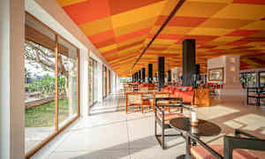 Et lyst og romslig rom med glassvegger, fargerikt rutemønster på taket og moderne sittemøbler. (AI-generert tekst)