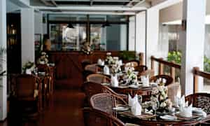 En restaurant med dekkede bord og blomster på hvert bord. (AI-generert tekst)