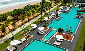 Et bassengområde ved en strand med solsenger og parasoller. (AI-generert tekst)