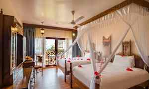 Hotellrom med to senger, dekorert med myggnett og røde blomsterblader. (AI-generert tekst)