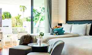 Hotellrom med dobbeltseng, sittegruppe og balkong med utsikt. (AI-generert tekst)