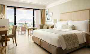 Et hotellrom med en stor seng, skrivebord og en balkong med utsikt. (AI-generert tekst)