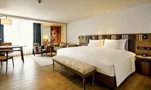 Moderne hotellrom med en stor seng, sittegruppe og arbeidsbord. (AI-generert tekst)