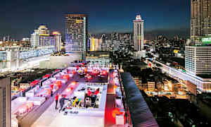 En takterrassebar med lys om kvelden og en bybakgrunn med høye bygninger. (AI-generert tekst)