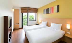 Et hotellrom med to enkeltsenger, lyse vegger og et vindu. (AI-generert tekst)