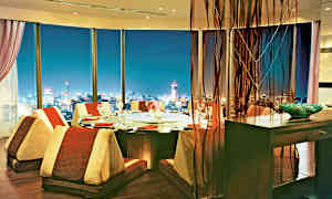 En elegant spisestue med panoramautsikt over en opplyst by om kvelden. (AI-generert tekst)