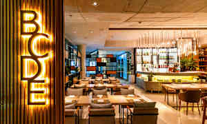 Et moderne restaurantområde med belysning, sitteplasser og en bardisk. (AI-generert tekst)