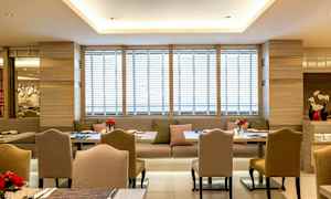 Bilde av en moderne restaurant med elegante stoler og bord samt sofaer, dekorert med friske blomster. (AI-generert tekst)