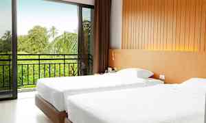 Et hotellrom med to enkeltsenger, en skyvedør fører til en balkong med utsikt over grønne trær. (AI-generert tekst)