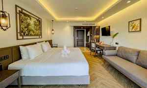 Moderne innredet hotellrom med dobbeltseng, sofa og arbeidsområde. (AI-generert tekst)