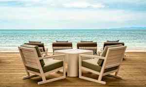 Tremøbler på en terrasse med utsikt over havet. (AI-generert tekst)