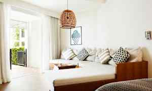 En stue med en hjørnesofa, puter og glassdører som leder til en uteplass. (AI-generert tekst)