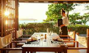 Utsikt over et dekket bord i en uteservering med solnedgang i bakgrunnen. (AI-generert tekst)