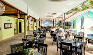 En utendørsrestaurant med bord og stoler ved et basseng. (AI-generert tekst)