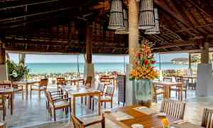 Uteservering med sitteplasser, blomsterdekorasjon og utsikt over havet. (AI-generert tekst)