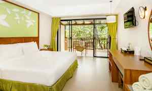 Et hotellrom med en dobbeltseng, skrivebord og utsikt mot en balkong. (AI-generert tekst)