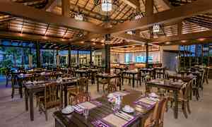 En åpen restaurant med trebord og stoler, dekket for måltider. (AI-generert tekst)