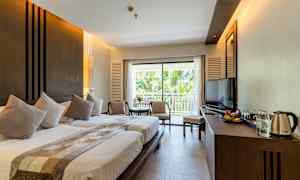 Et hotellrom med to senger, en sittegruppe, en balkong og en TV. (AI-generert tekst)